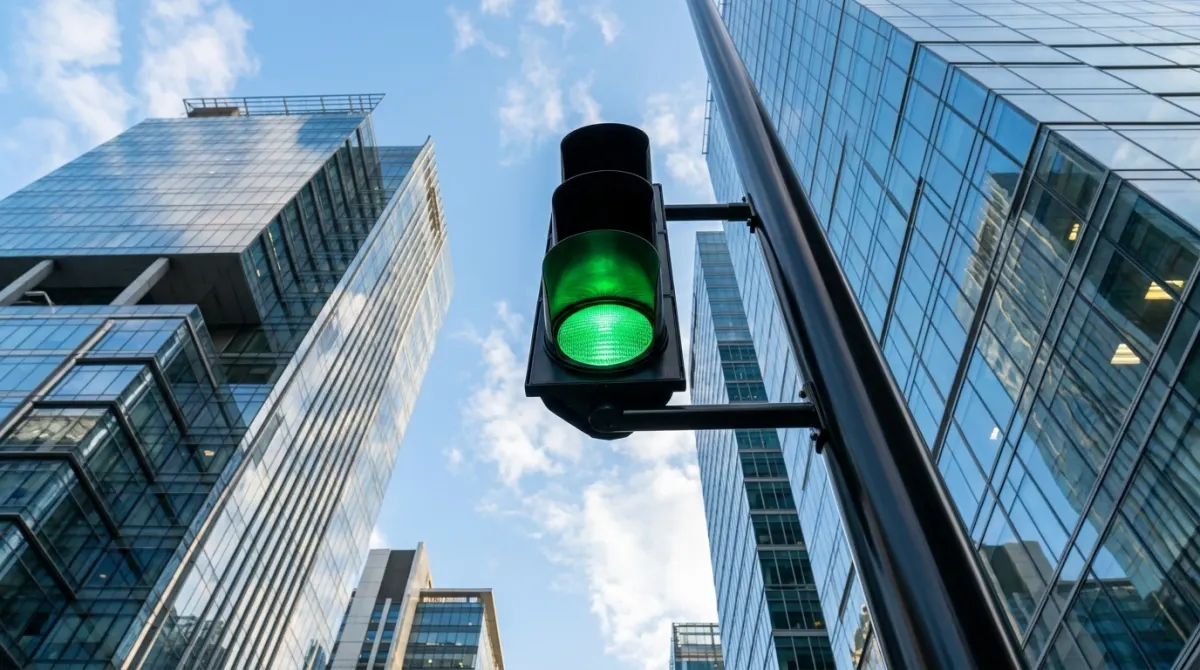 Green traffic light glowing against modern commercial buildings and blue sky, representing fast approval for property finance